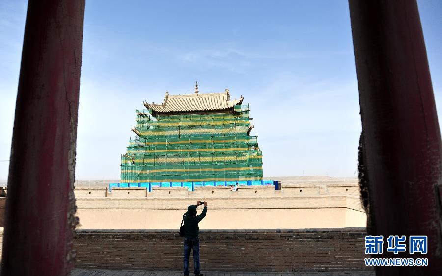 一名游客在正在維修的嘉峪關(guān)城樓上拍照