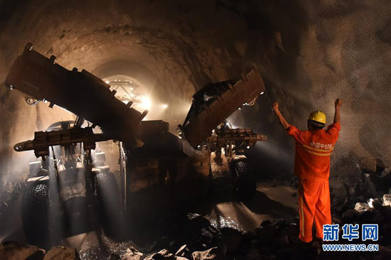 7月16日，工人在隧道貫通點(diǎn)指揮車輛清運(yùn)石方。