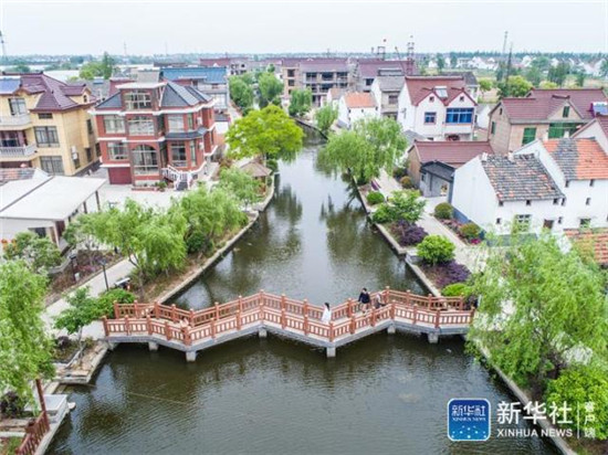 4月21日，空中俯瞰浙江省嘉善縣干窯鎮(zhèn)的新涇港河道（無人機拍攝）。經(jīng)過整治的河道水清樹綠，已成為美麗的鄉(xiāng)村公園。曾經(jīng)的新涇港，是當?shù)厝罕娍谥械摹澳印?、“黑臭河”，?jīng)過三年左右的整治，新涇港水質(zhì)保持三類水標準,兩岸綠樹成蔭、粉墻黛瓦，呈現(xiàn)出典型美麗江南村落的畫面。新華社記者 徐昱 攝
