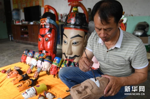 方文展在為一個(gè)毛南族儺面上涂料