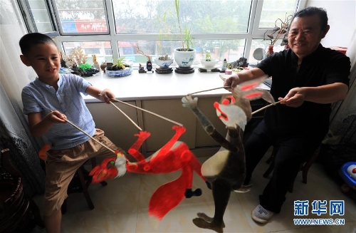 李衛(wèi)與外孫一起表演皮影（7月11日攝）。