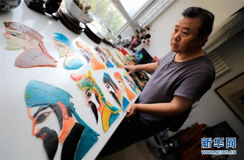 李衛(wèi)展示自己制作的“濟南名人臉譜”系列的皮影人偶（7月5日攝）。