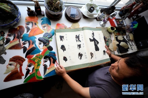 李衛(wèi)展示自己制作的“濟南名人臉譜”系列的皮影人偶。