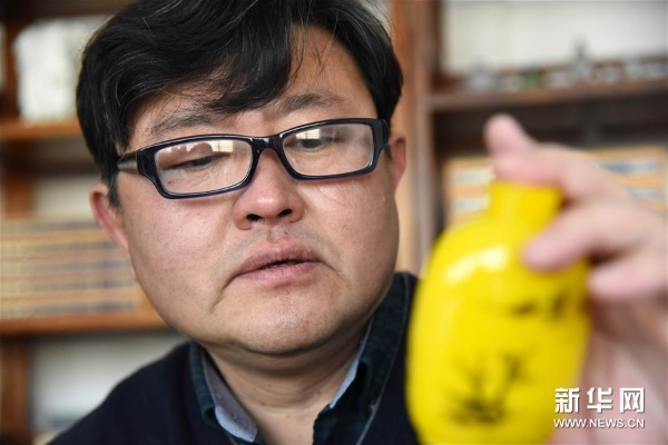 孫云毅在查看一只剛剛畫完的雞油黃鼻煙壺 孫云毅在查看一只剛剛畫完的雞油黃鼻煙壺