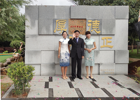 陸校長與畢業(yè)生家長代表在家長贈送的畢業(yè)墻前合影。記者 張薇 攝