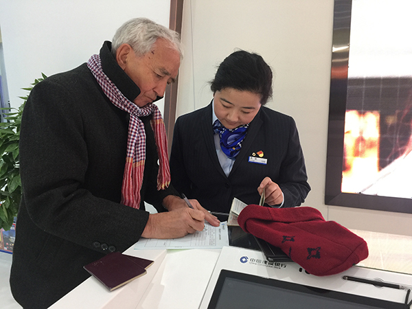 建行昆明城北支行營業(yè)室員工正在協(xié)助一位外籍客戶填寫表單。記者 張薇 攝