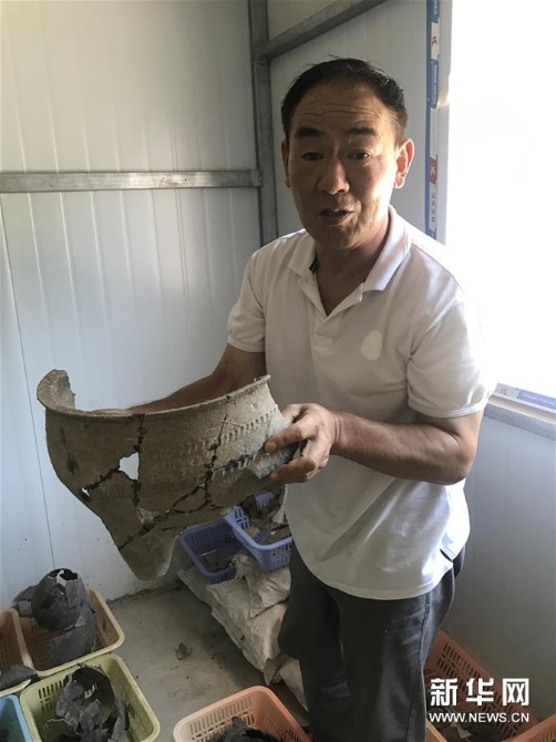 考古人員張官獅介紹陶寺遺址出土文物（8月13日攝）。