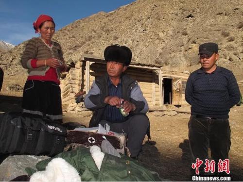 圖為居馬泰·俄白克(中)在包扎墩牧區(qū)牧民發(fā)放藥品。