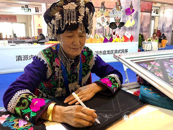 3 身穿彝族服飾的游定美正在用筆在布上畫圖案 記者蘇雯芊 攝
