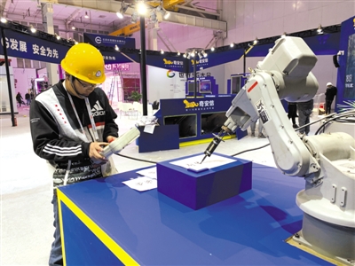 昨日，參展單位正在布展，工作人員調(diào)試會(huì)“寫字”的機(jī)械臂。圖片參展單位提供