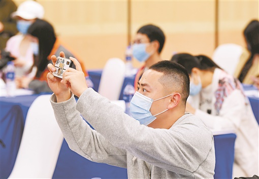 3月25日，湖南省政府新聞辦召開的統(tǒng)籌推進疫情防控和經(jīng)濟社會發(fā)展第六場新聞發(fā)布會在長沙舉行。圖為與會一位記者在發(fā)布會現(xiàn)場拍攝。徐行 攝