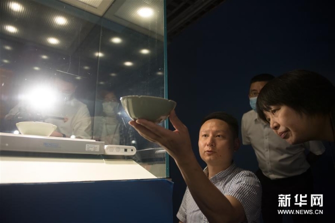 4劉杰（前左）在浙江省博物館向陶瓷部主任沈瓊?cè)A（前右）展示自己復(fù)刻的“馬蝗絆”（5月15日攝）。 新華社記者 翁忻旸 攝