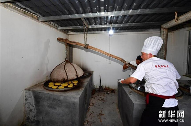 9月13日，在河南省商丘市夏邑縣太平鎮(zhèn)聶陳樓村，張旭（右）將月餅上爐。新華社記者 馮大鵬 攝