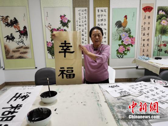 80歲高齡的曲奶奶展示自己寫(xiě)的書(shū)法作品。劉歡 攝