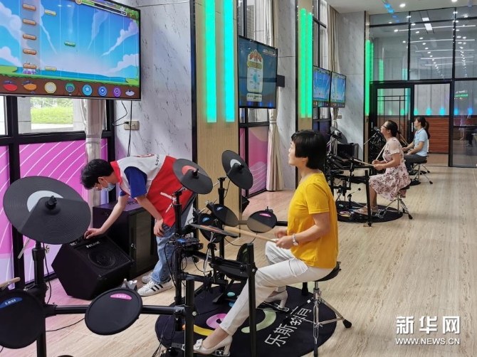 在湖南長(zhǎng)沙縣文化館的“悅藝空間”里，人們?cè)隗w驗(yàn)電子鼓（6月18日攝）。