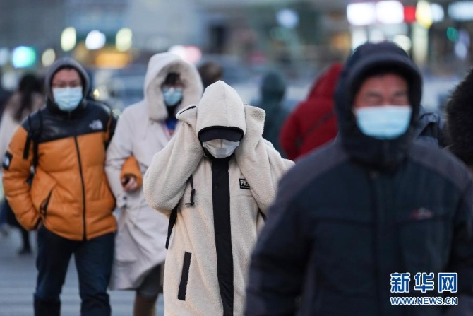 12月29日，一名行人捂著耳朵走過北京朝陽區(qū)青年路和朝陽北路路口。當(dāng)日，入冬最強(qiáng)寒潮來襲，多地迎來今冬最寒冷天氣。新華社記者鞠煥宗 攝