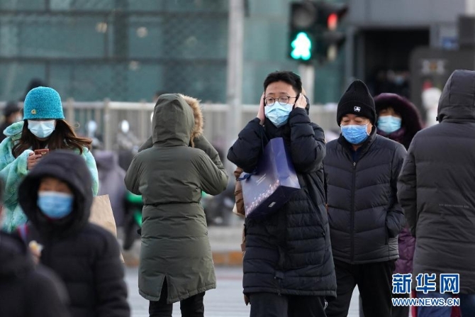 12月29日，一名行人捂著耳朵走過北京朝陽區(qū)青年路和朝陽北路路口。當(dāng)日，入冬最強(qiáng)寒潮來襲，多地迎來今冬最寒冷天氣。新華社記者鞠煥宗 攝1