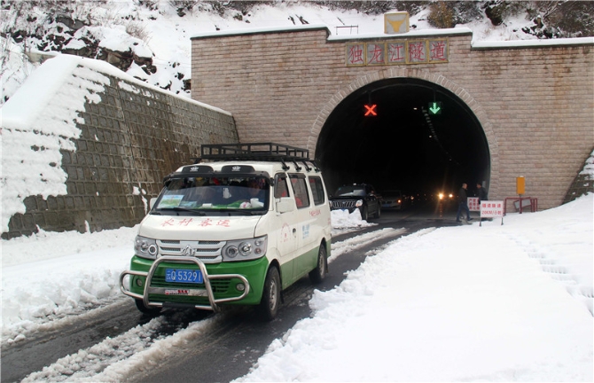王軍的農(nóng)村客運車輛雪花飄飄中駛出獨龍江公路高黎貢山隧道。王靖生攝.jpg