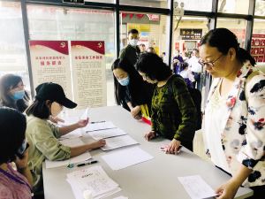 家長到社區(qū)服務(wù)窗口領(lǐng)取新生入學(xué)通知書。