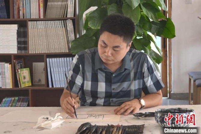 “榆木先生”龐志強(qiáng)在作畫。　張俊 攝