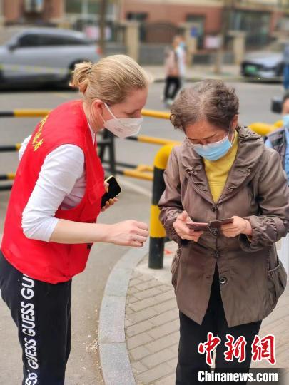 伊莉娜引導前來進行核酸檢測的社區(qū)居民進行登記?！∫晾蚰缺救斯﹫D