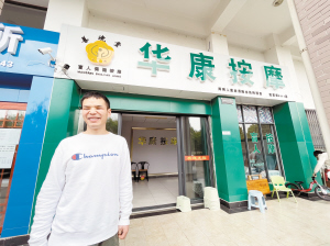 胡小磊站在自己的按摩店前。