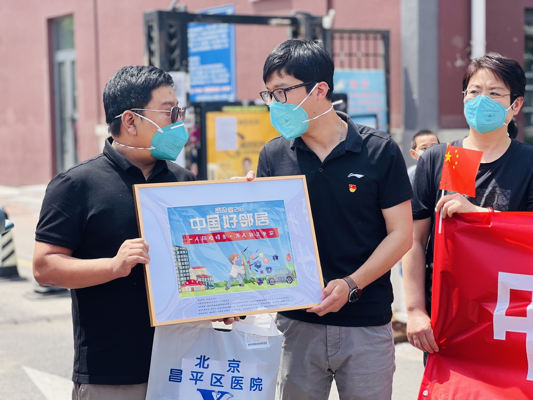 張旭（左一）康復后回到小區(qū)，收到了一幅主題為“中國好鄰居”的手工藝品禮物（5月18日攝）。新華社發(fā)（周紫欣 攝）