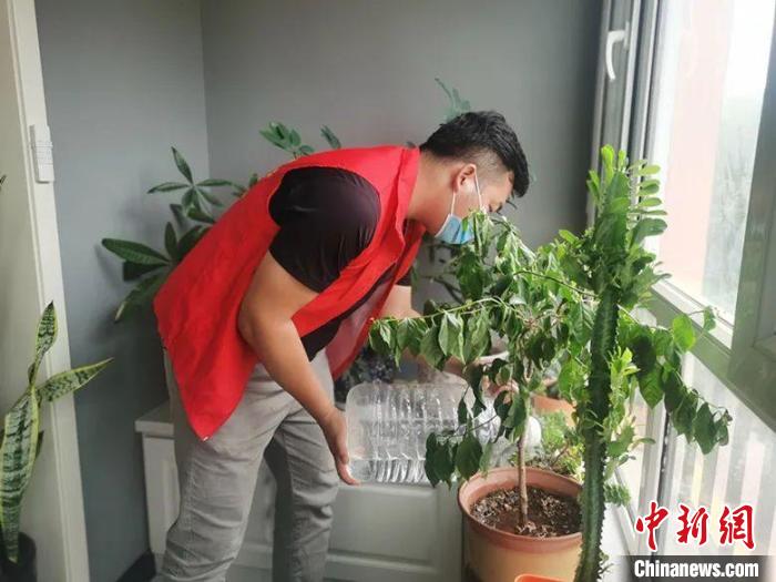 一名志愿者幫助家中無人住戶澆花?！∮刃び?攝