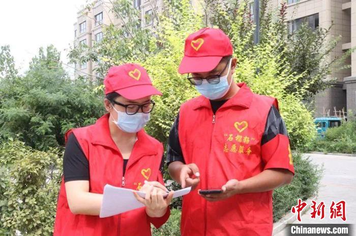 兩名志愿者商量為小區(qū)居家休息人員配送物資事宜?！堒坝?攝