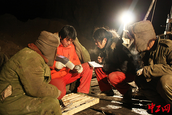 萬建領(lǐng)（左二）針對鉆機(jī)取出的巖心進(jìn)行野外快速分析測試、