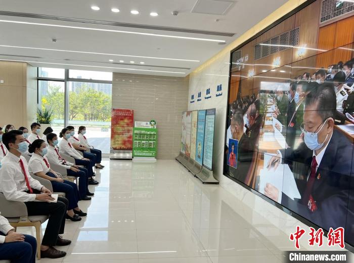 黃釗逸(第一排左一)與同事一起，通過(guò)電視收看黨的二十大開幕直播?！⊥鯃?jiān) 攝