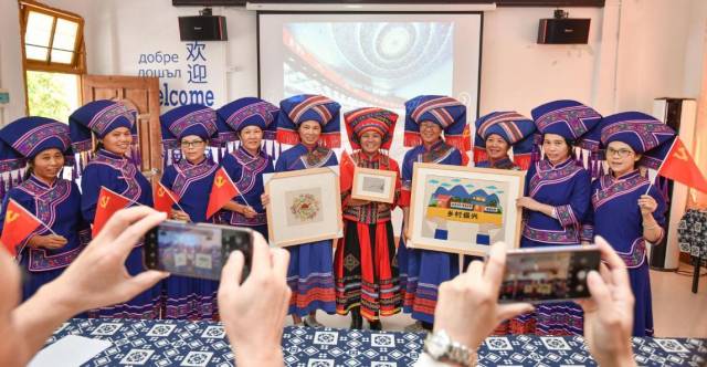 在清遠(yuǎn)連山嘉田錦繡專業(yè)合作社，收聽收看黨的二十大開幕會直播后，壯族繡娘舉起錦繡作品合影。南方日報(bào)記者 曾亮超 攝