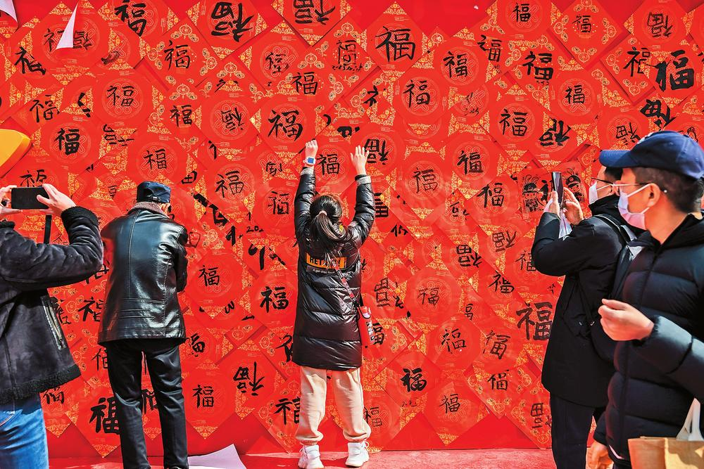 春節(jié)期間，昆明市新紀元廣場舉辦“七彩頌福墻南屏迎新春”活動，眾多市民前來寫春福、貼春聯(lián)，打卡福字墻。本報記者 胡妤雅 實習(xí)生 吳文博 攝