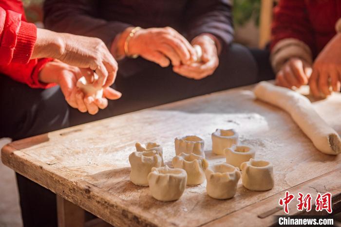 村民們將面團(tuán)捏成各種造型，制做面燈?！￡惞饨?攝