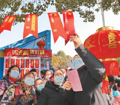 江蘇省南通市組織20個(gè)城市社區(qū)開展“一刻鐘便民生活圈”試點(diǎn)。2023南通鄰里生活節(jié)活動(dòng)上，近50家品牌連鎖企業(yè)、醫(yī)療服務(wù)機(jī)構(gòu)、電商平臺(tái)、行業(yè)協(xié)會(huì)等商貿(mào)企業(yè)，將優(yōu)惠商品、優(yōu)質(zhì)服務(wù)送到居民家門口，提供消費(fèi)便利，展現(xiàn)城市溫度。活動(dòng)中，購花燈、猜燈謎、專家義診、家政服務(wù)、優(yōu)惠商品等內(nèi)容豐富多彩。圖為居民在猜燈謎。  許叢軍攝（人民圖片）